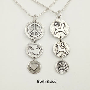 Both sides of the Alpaca or Llama Reversible Tri-Coin Drop Pendant - one side with pronking animals and sun, moon and star accents - the reverse side has a peace sign, dove and a heart - Sterling Silver